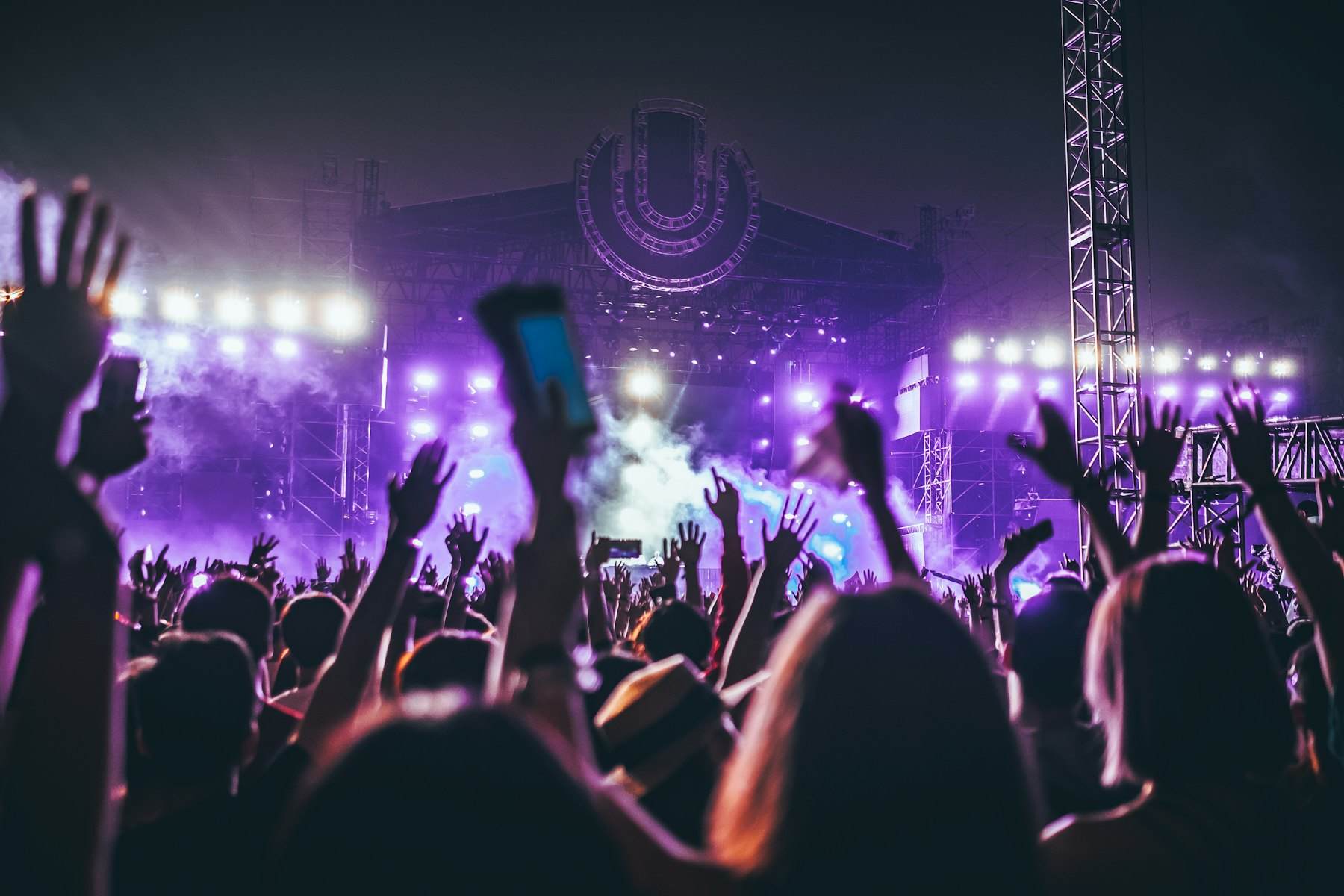 Stage lighting beams cutting through haze above a crowd
